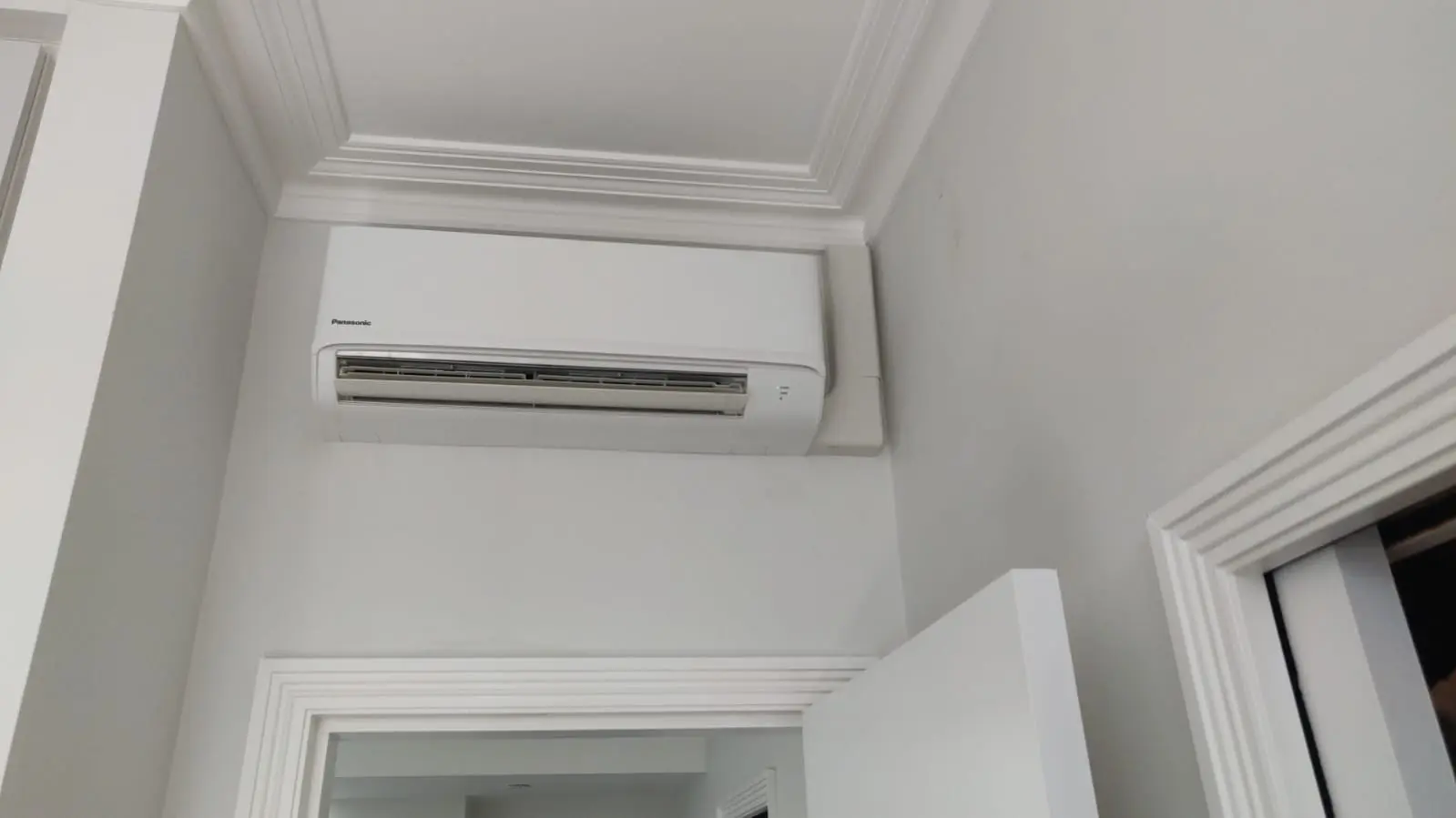 Residential Panasonic air conditioner installed high on a white wall in Wandsworth London