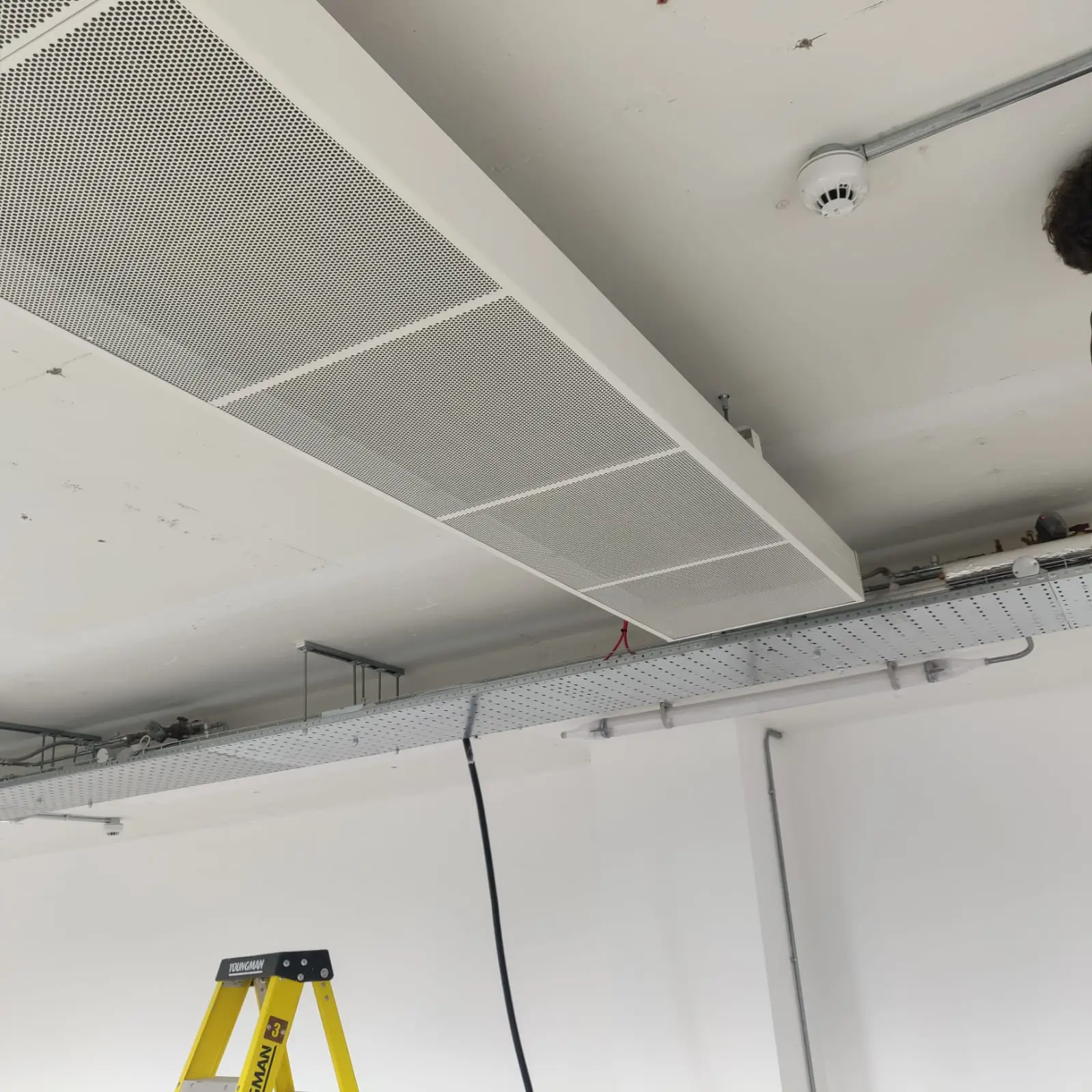 Ceiling-mounted air conditioning unit with ventilation grilles and cable trays